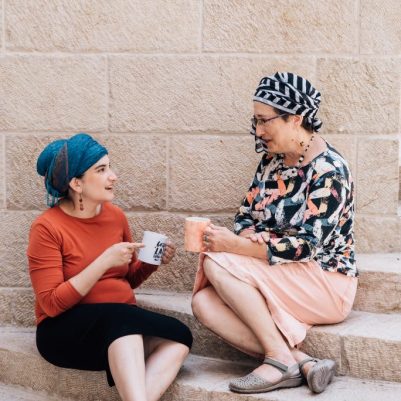 Two women talking outside holding cups