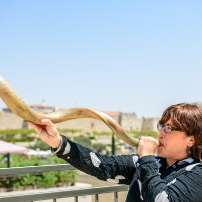 Woman blowing shofar outside 3