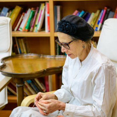 Older woman knitting in library 1