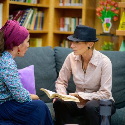 Two women discussing book in library 2