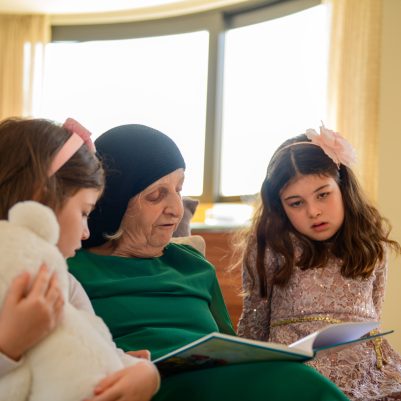 Grandmother reading book to grandchildren