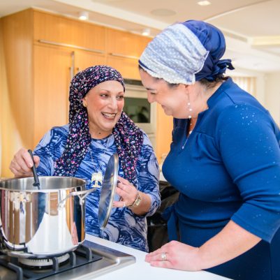 Two women laughing and talking while cooking