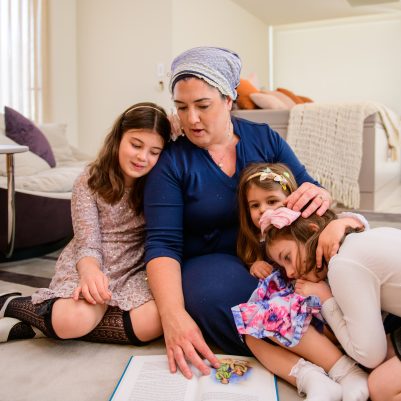 Mother reading a book to daughters on carpet 2