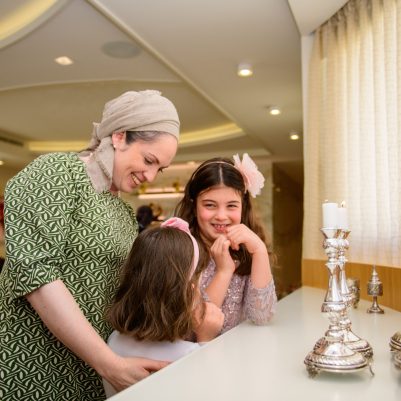 Mother and daughters getting ready to light Shabbat candles
