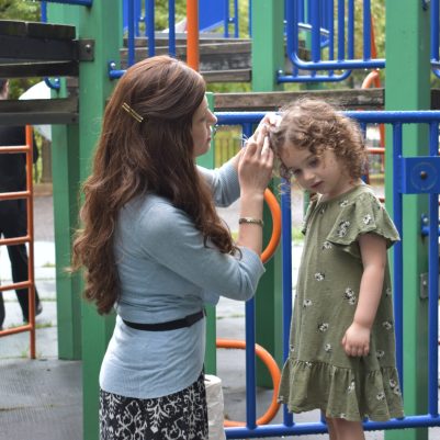 Mother fixing daughter's hair at the park