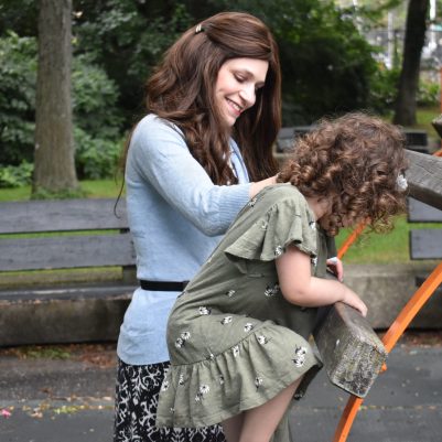 Mother helping daughter at park on jungle gym 1
