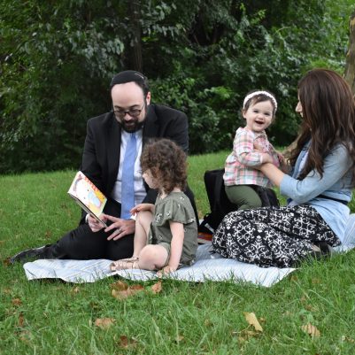Family sitting on grass in park talking 2