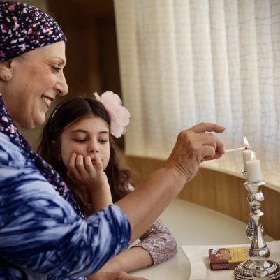 Grandmother and grandaughter lighting Shabbat candles
