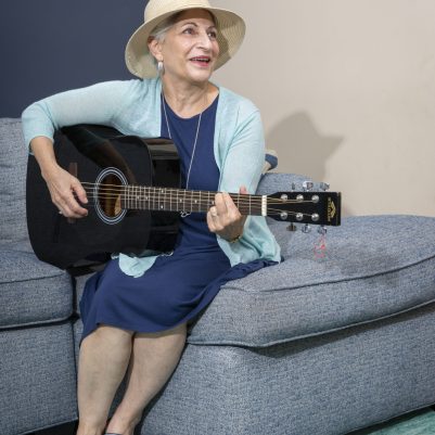 Woman playing guitar on couch