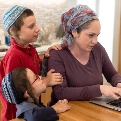Mother working on laptop with sons interrupting