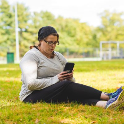 Woman sitting on grass looking at phone