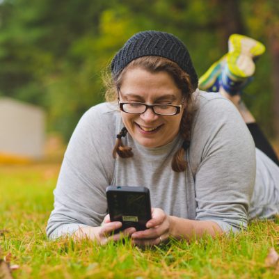 Woman sitting on grass smiling at phone