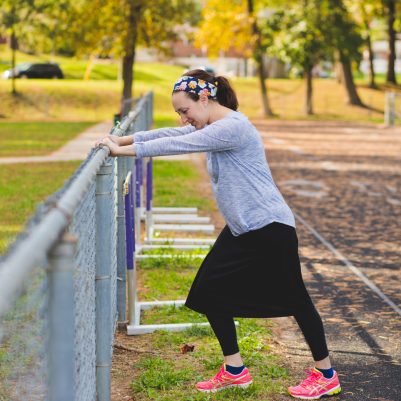 Woman stretching next to fence