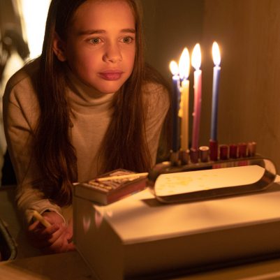 Girl looking at lit chanukkia