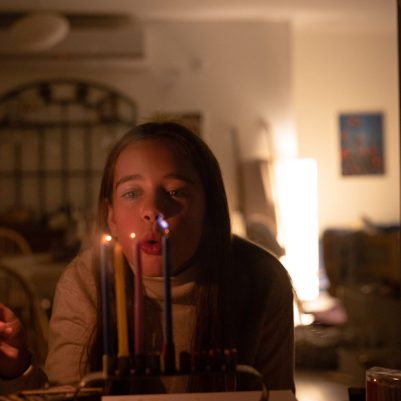 Girl blowing out Chanukah candles