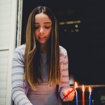 Young woman lighting chanukkia 1