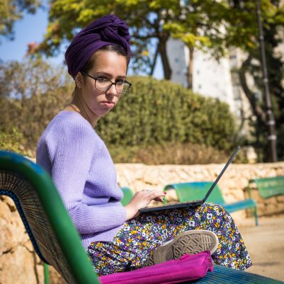 Woman sitting on bench working on laptop