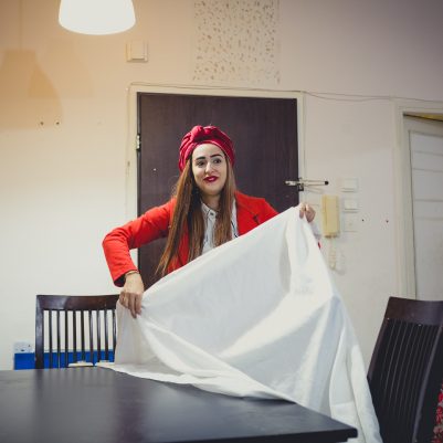 Woman putting tablecloth on table