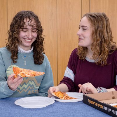 Two young women eating pizza 2