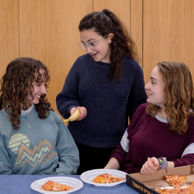 Young woman offering fruit to friends eating pizza 1