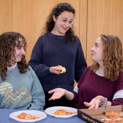 Young woman offering fruit to friends eating pizza 2