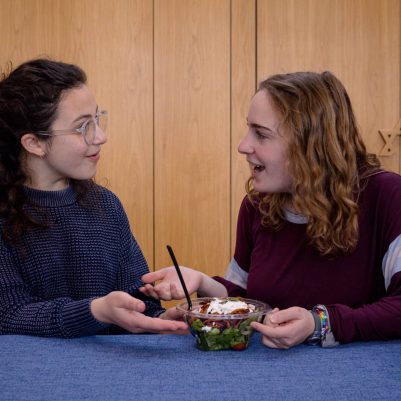 Two young women eating salad