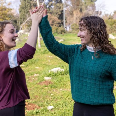 Two young women high-fiving outside 7