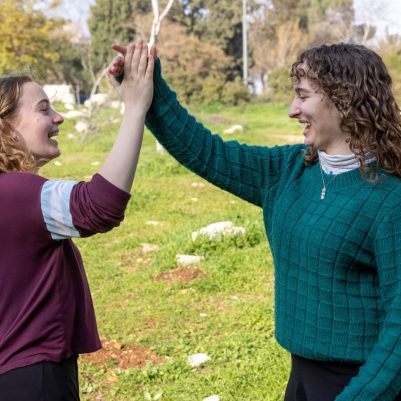 Two young women high-fiving outside 8