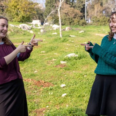 Two young women pointing at each other