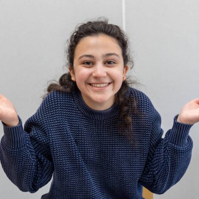 Young woman smiling and shrugging shoulders