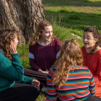 Group of young women sitting in a circle on grass 1