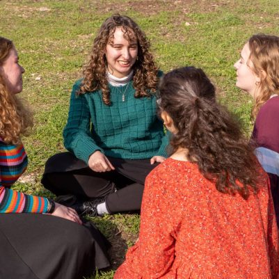 Group of young women sitting in a circle on grass 2