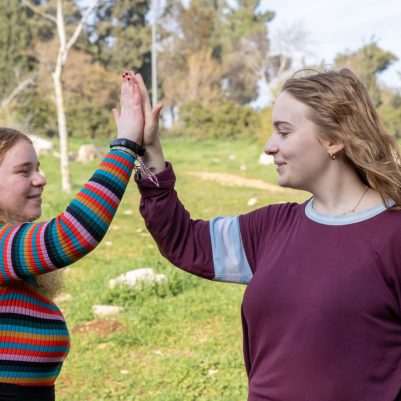Two young women high-fiving outside 1