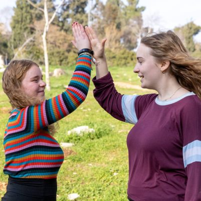 Two young women high-fiving outside 2