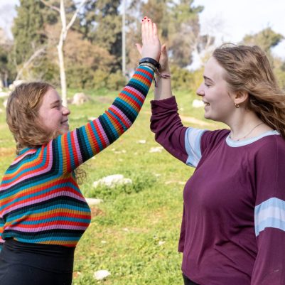 Two young women high-fiving outside 3