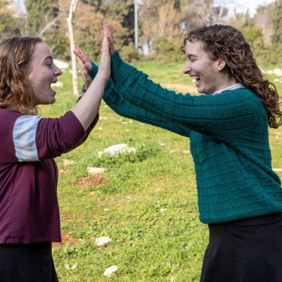Two young women high-fiving outside 4
