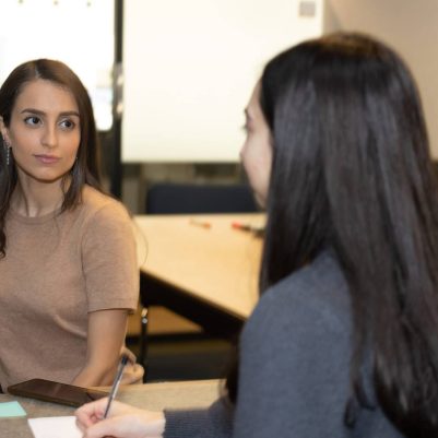 Two women in meeting taking notes