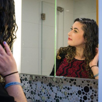 Woman fixing hair in front of mirror 1