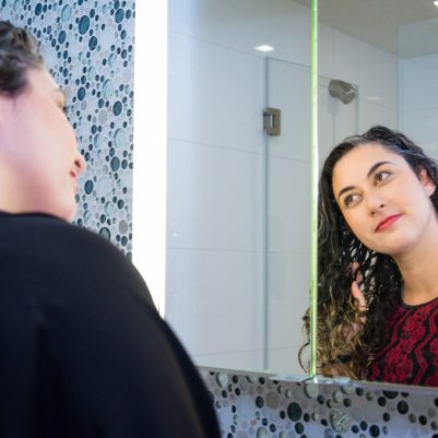 Woman fixing hair in front of mirror 2