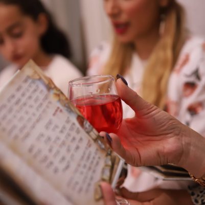 Woman holding cup and Haggadah at Seder