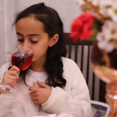 Girl drinking grape juice at Seder