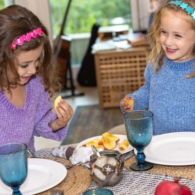 Two smiling girls at Rosh Hashana table