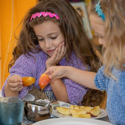 Two girls dipping apple in honey 1