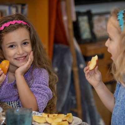 Two girls dipping apple in honey 3