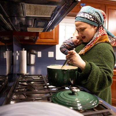 Woman holding baby stirring pot 2