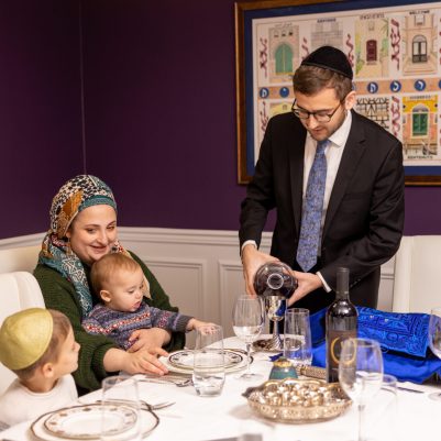 Father pouring grape juice for Kiddush at table with family
