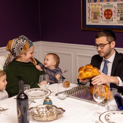 Father making Hamotzi at Shabbat table with family 2