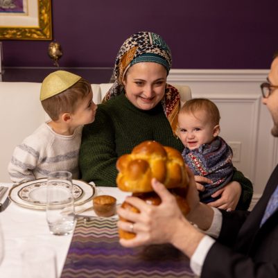 Father making Hamotzi at Shabbat table with family 3