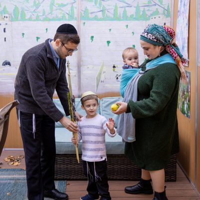 Parents helping son shake lulav and etrog 1