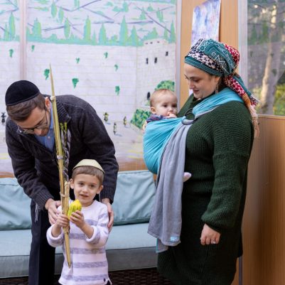 Parents helping son shake lulav and etrog 2